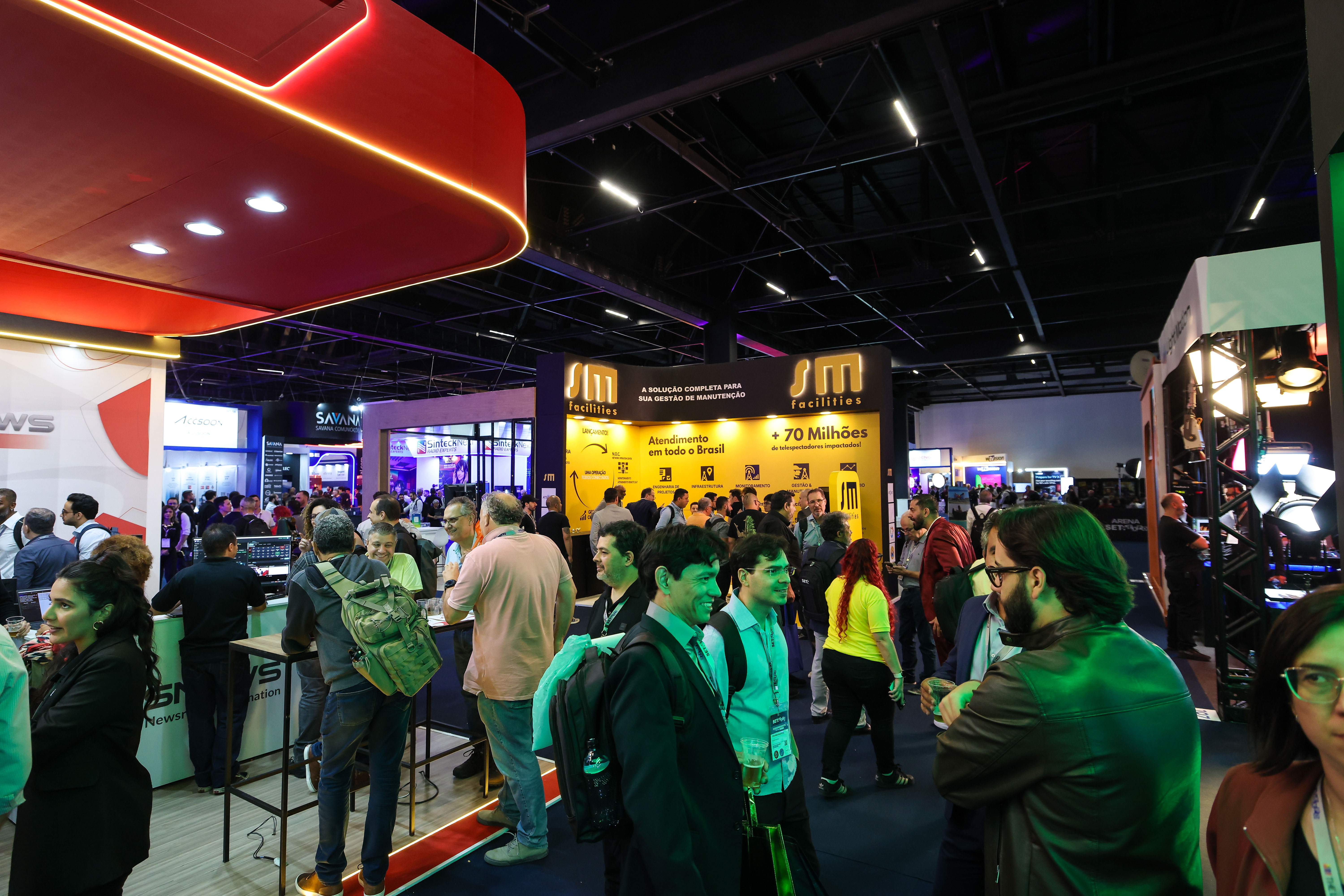Feira corporativa com estandes e participantes em um pavilhão de eventos